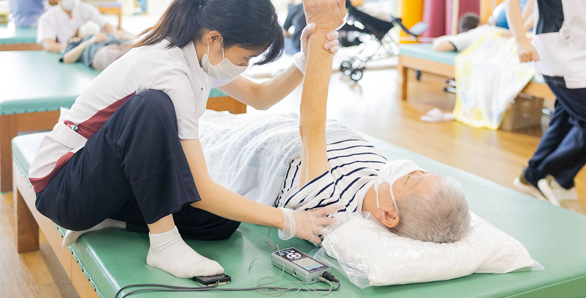 腕に電極を装着し、神経電気刺激療法を行っている場面